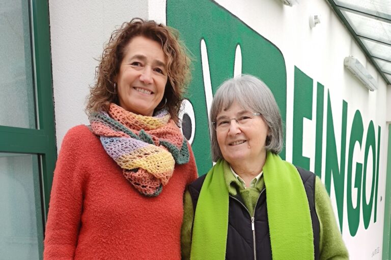 María Seijas y Siña Fernandez Puentes posan delante del mural del logo del colexio Fingoi.